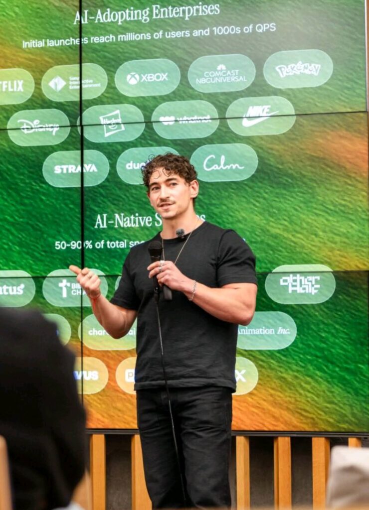 A speaker presenting beside a large AI map display.